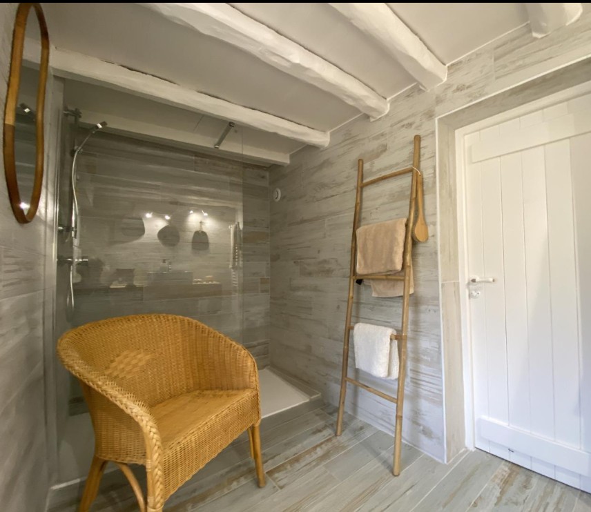 Salle d'eau avec douche italienne et fauteuil en rotin