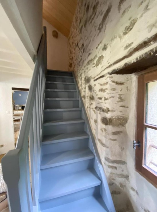 Escalier bleu en bois sur mur en pierres