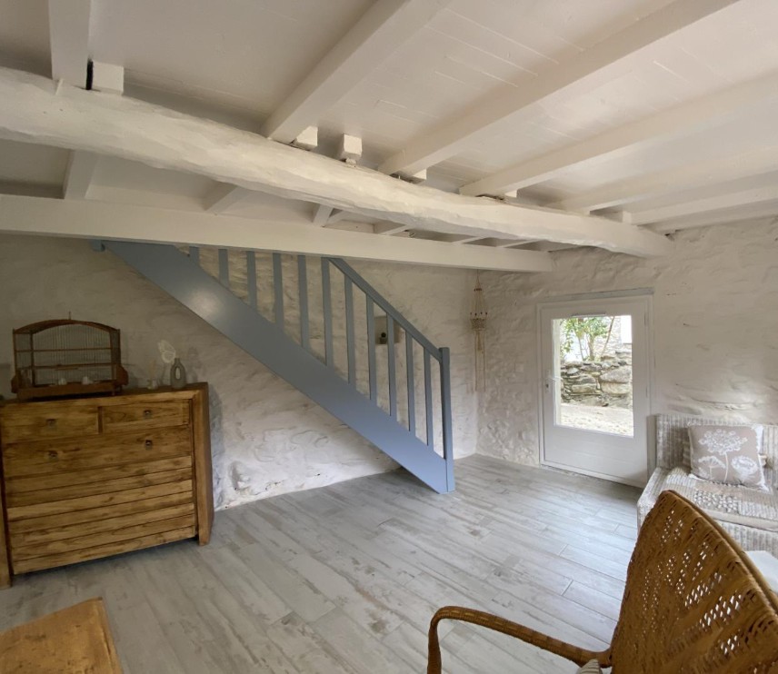 Pièce détente au RDC bas avec escalier bleu et pierres apparentes